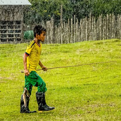 Un niño del pueblo indígena huitoto de la Amazonia regresa tras una dura jornada de pesca a causa de la lluvia intensa. Huitoto, Colombia, 2014.