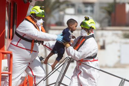 Dos trabajadores de la Guardamar Talia de Fuerteventura trasladan a un niño que ha sido rescatado de una embarcación junto a otras 94 personas este sábado.