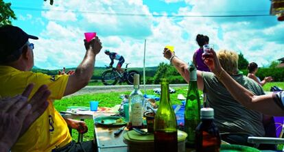 Aficionados apostados en los arcenes de la carretera disfrutan del Tour de Francia.