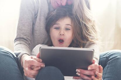 Una niña juega con su madre con la 'tablet'.