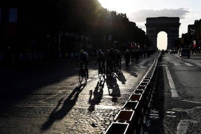 Los ciclistas recorren la avenida de los Campos Elíseos con el Arco de Triunfo de fondo.