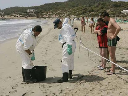 Varios operarios limpian de residuos contaminantes la playa de En Bossa (Ibiza).