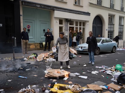 Una trabajadora de un restaurante apaga un pequeño fuego con agua durante la protesta en París, el jueves.