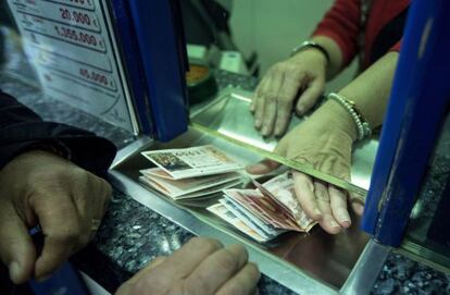 Un home compra diversos d&egrave;cims de la Loteria de Nadal.