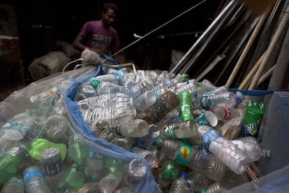 Un hombre acarrea una red llena de botellas de pástico a las afueras de Gauhati.