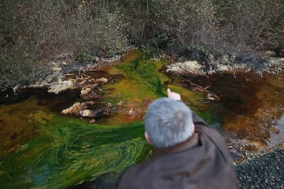 Un vecino de Touro muestra el drenaje &aacute;cido de mina en el agua de la zona.