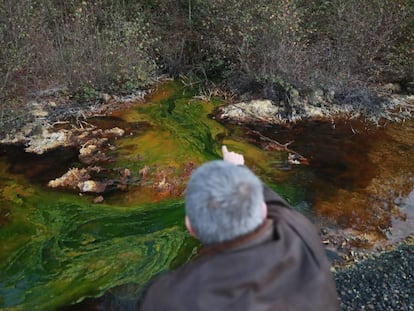 Un vecino de Touro muestra el drenaje &aacute;cido de mina en el agua de la zona.