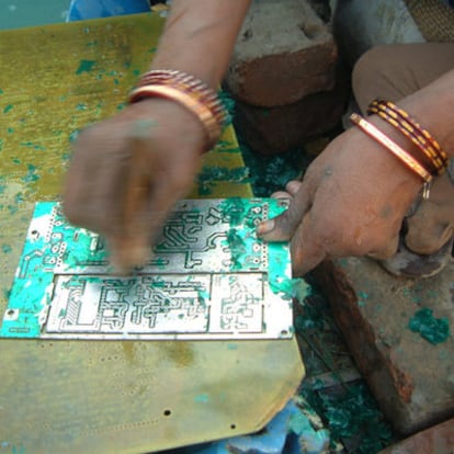 Una mujer limpiando placas de circuitos electrónicos en un basurero de Calcuta.