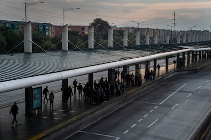 Los usuarios hacen fila para abordar el transporte público al amanecer en Bogotá. 