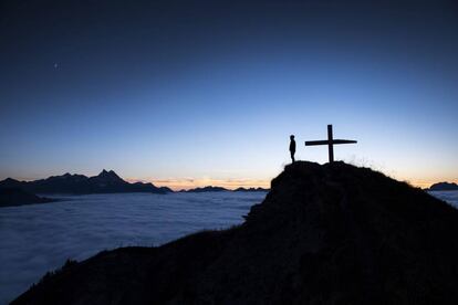 Una persona observando el mar de nubes al atardecer en la cumbre del Croix des Chaux/Chaux Ronde, en el oeste de Suiza.