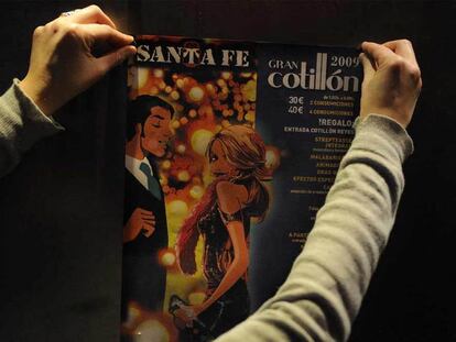Una joven coloca un cartel que anuncia un cotillón de Nochevieja en un bar de Vitoria.