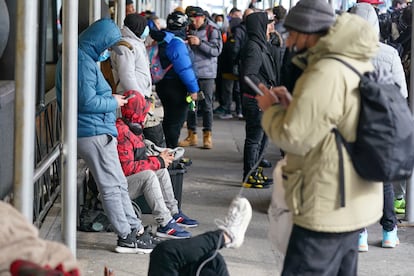 Recent immigrants to the United States sit with their belongings on the sidewalk in front of the Watson Hotel in New York, Monday, Jan. 30, 2023.