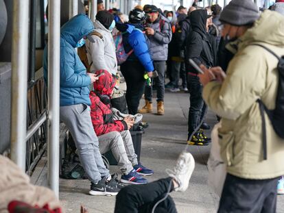 Recent immigrants to the United States sit with their belongings on the sidewalk in front of the Watson Hotel in New York, Monday, Jan. 30, 2023.