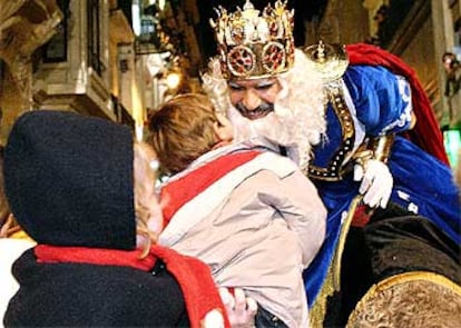 El Rey Melchor, cariñoso, besa a todos los niños que se le acercan a su paso por las calles de la localidad alicantina de Alcoi, un lugar muy especial para los Magos de Oriente, porque allí se celebra la cabalgata desde tiempos inmemoriales. Por cierto, cómo se parece este Rey Mago al presidente del Gobierno, José María Aznar.