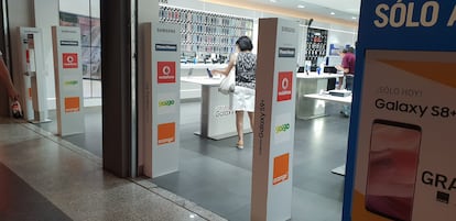 Varios clientes consultan las características de móviles en una tienda de telefonía.