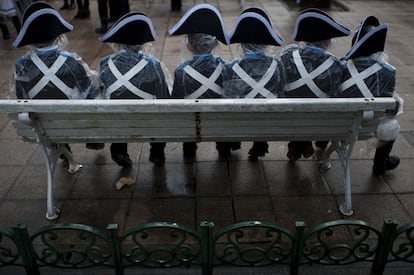 Varios tamborileros participantes en el desfiles infantil descansan sentados en un banco.