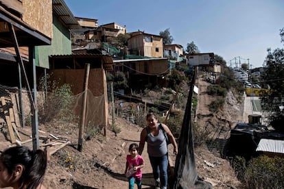 Mónica Oviedo camina hacia su casa junto a su hija en el campamento Toma la Cancha, en una ladera de la comuna Lo Barnechea en Santiago. El poder político del país creía que el drama de la pobreza había logrado controlarse en sus años de bonanza económica, pero las movilizaciones que estallaron a partir del 18 de octubre de 2019 impactaron en la actividad productiva y la pandemia de coronavirus golpeó cuando la economía salía a flote a principios de 2020.