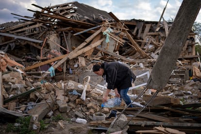 Anna Shevchenko, 35, waters the few flowers that survived in the garden of her home in Irpin, near Kyiv, on Tuesday, May 3, 2022. There are no longer any walls. The broad wooden roof beams lie splintered and scattered, and random pieces of clothing dangle from twisted water pipes. But among the rubble of what used to be her home, the house her grandparents built, Anna Shevchenko saw a glimmer of hope. (AP Photo/Emilio Morenatti)