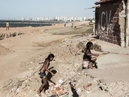 Crianças brincam em praia no Pirambu. Ao fundo, pichação do Comando Vermelho.