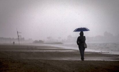 Una persona pasea por la playa de la Malvarrosa bajo la lluvia que se registra hoy en prácticamente toda la Comunidad Valenciana.