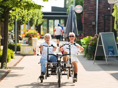 Una anciana pasea junto a un cuidador en las calles de la residencia para enfermos con alzhéimer de Hogeweyk (Holanda).