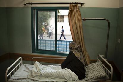 Una mujer embaraza mira por la ventana desde la cama de su habitación en el área de maternidad, que da a la morgue. Ella está a punto de dar a luz.