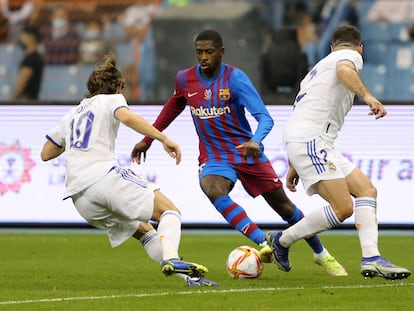 Dembélé intenta sortear el marcaje de Modric y Carvajal.