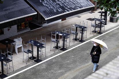 Una mujer pasa por delante de una terraza de un bar vacía, este lunes en Oviedo.