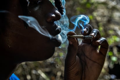 A person smokes a joint in a forest in Kenya.