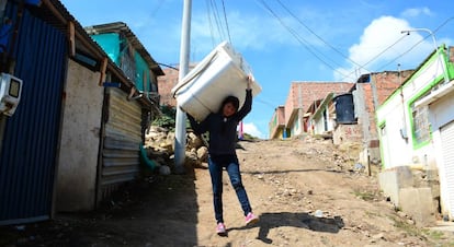 Jessica Hernández carga con una lavadora para alquilarla en Soacha, un barrio marginal de Bogotá (Colombia).