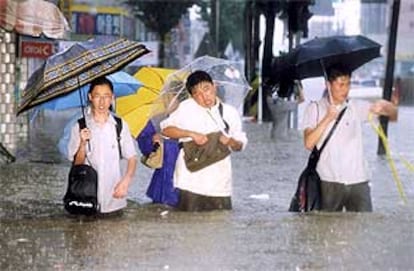 Varios estudiantes surcoreanos se abren paso por una calle anegada bajo una lluvia torrencial.