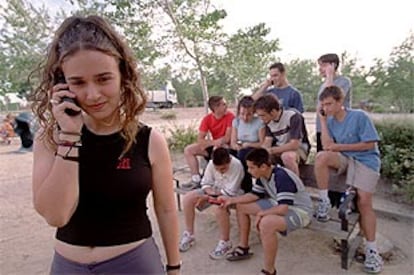 Un grupo de adolescentes  utiliza sus móviles en un parque de Madrid.