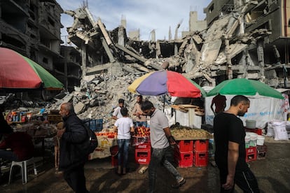 Palestinian men walk past kiosks set up next to buildings of the Nuseirat refugee camp in the Gaza Strip, on April 5, the last Friday of Ramadan.