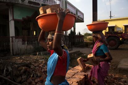 Dos mujeres llevan barreños llenos de ladrillos para la construcción de una casa en Bodhali. En este tipo de poblados, las mujeres suelen trabajar tanto o más que los hombres, además de ocuparse de las tareas de la casa y de los niños.