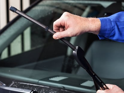 Un hombre cambiando las escobillas en su coche.