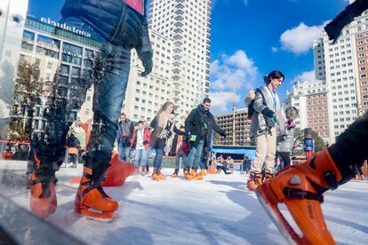 Varias personas patinan sobre hielo en la plaza de España en Madrid, este sábado. 