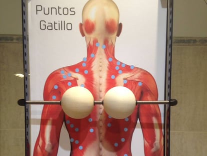 The massage device consists of two wooden balls held in place by a metal rod that is attached to a frame.