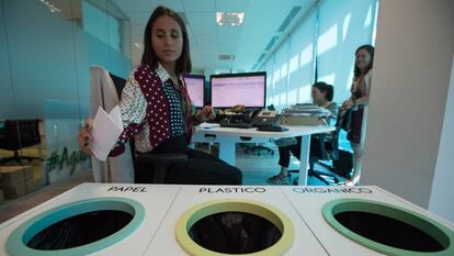 Una trabajadora de la empresa de cosmética Yves Rocher tira un papel en las papeleras de reciclaje que hay en las oficinas de la compañía en Madrid.