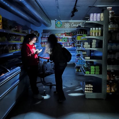 A worker assists a customer with a torch at a supermarket during a power outage which hit large parts of Spain, in Barcelona, Spain April 28, 2025. REUTERS/Nacho Doce     TPX IMAGES OF THE DAY     