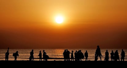 Numerosos jóvenes recogen sus deshechos tras ver amanecer, este lunes, en la playa de la Malvarrosa de Valencia después de celebrar la noche de San Juan.