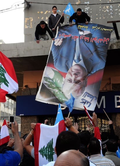 Partidarios de Hariri arrancan un cartel con el rostro del nuevo primer ministro, Najib Mikati, en la ciudad de Tripoli, Líbano.