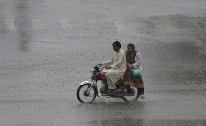 Un viajero paquistaní conduce su motocicleta a través de la lluvia del monzón en Lahore.