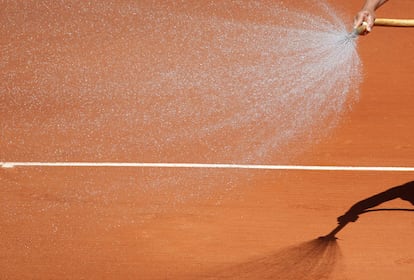 Un operario riega la arena en Roland Garros durante el descanso entre dos sets del partido entre el francés  Julien Benneteau y el español David Ferrer.