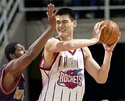 Yao Ming protege el balón ante la defensa del brasileño de los Nuggets de Denver, Nene Hilario.
