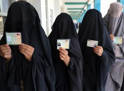 Mujeres afganas ataviadas con <i>burkas</i> enseñan sus carnés de electoras mientras hacen cola para votar en Kandahar, el pasado 20 de agosto.