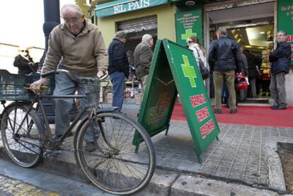 Un hombre aparca su bicicleta para hacer cola ante una de las farmacias abiertas por los servicios mínimos ayer en Valencia.