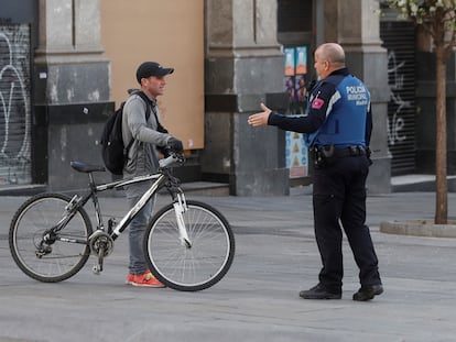 Un policía informa a un ciudadano de la prohibición de montar en bici tras la aprobación, este domingo, del real decreto que establece las medidas del estado de alarma para hacer frente a la pandemia del Covid-19.