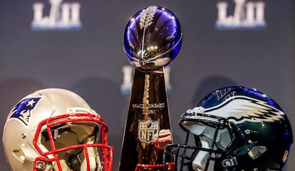 O capacete branco dos Patriots e o capacete verde dos Eagles ao lado do troféu Vince Lombardi.