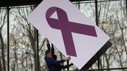 Minuto de silencio en el Ministerio de Sanidad. Un operario coloca un panel con una lazo gigante rosa en contra de la violencia de g&eacute;nero. 