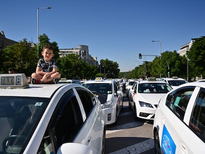 Un niño, en el capó de un taxi durante la protesta de taxistas de esta mañana.